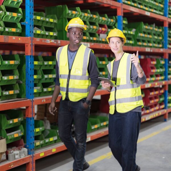 two employees in safety outfits walking an aisle
